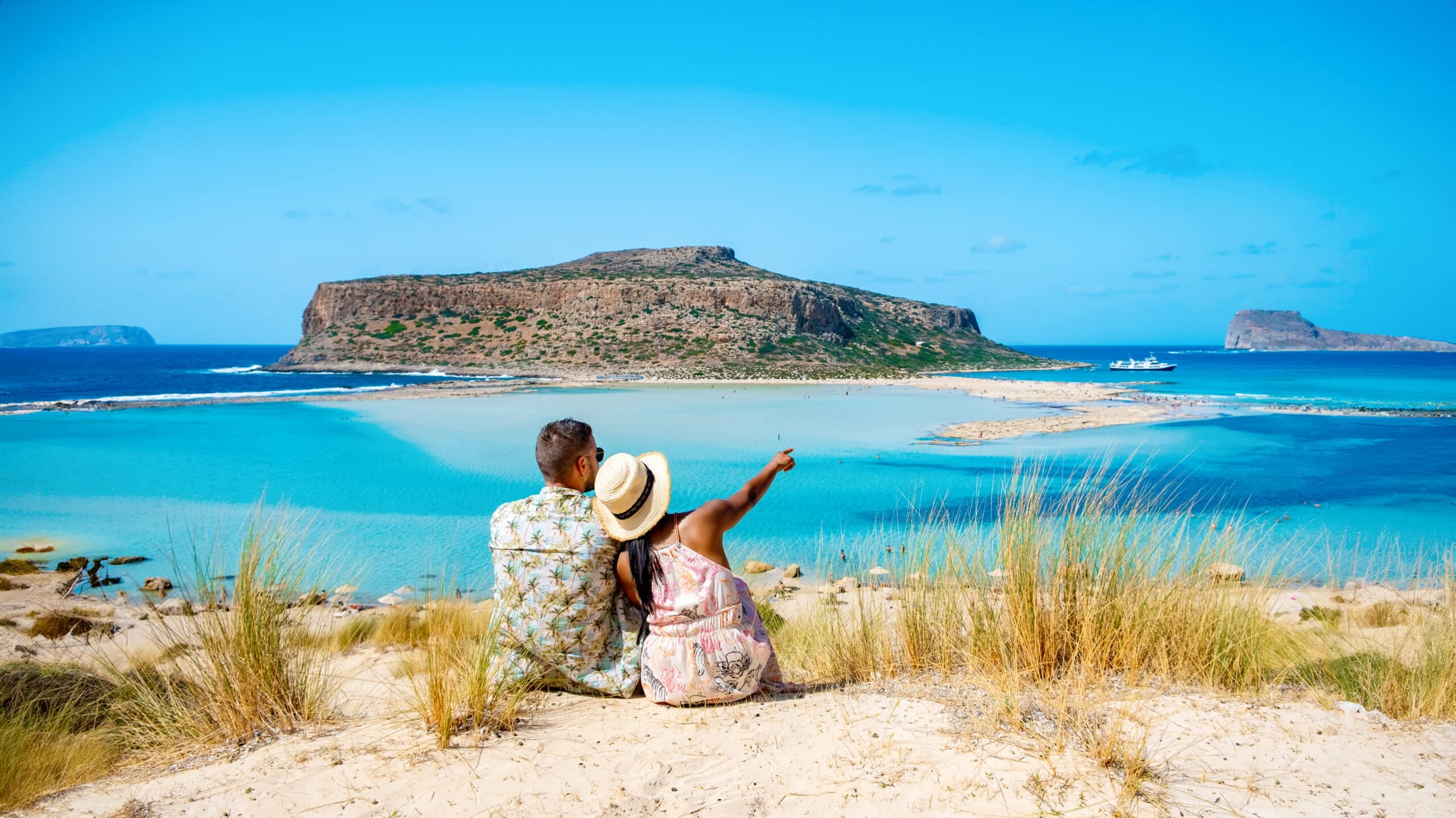 Crete Greece Balos Lagoon Crete island, Tourists relax at the crystal clear ocean of Balos Beach. a couple of men and a woman visit the beach during a vacation in Greece on a sunny day